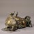 This is a cast bronze figurine featuring a reclining ox accompanied by a small human figure (a herder) seated at its rear....