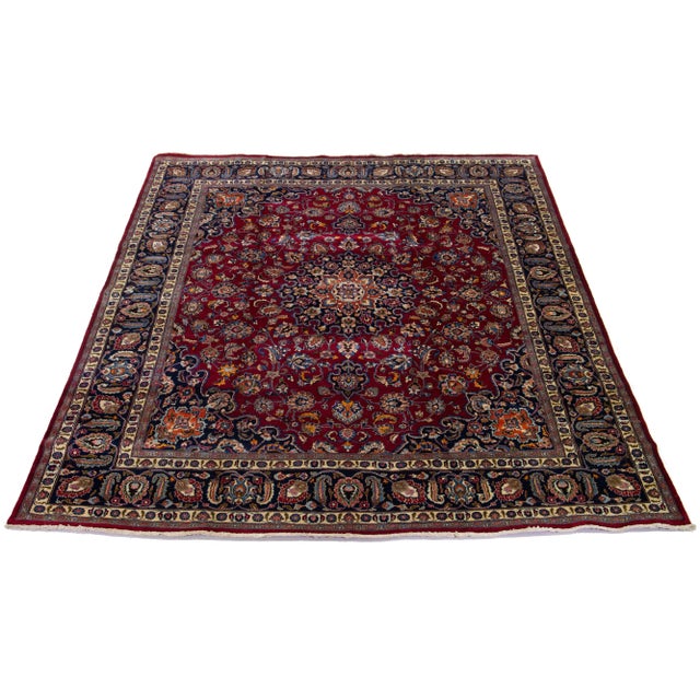 1960s vintage handmade Mashad wool rug has a red field and multicolor accents in a rosette motif. this rug measures 9'7" x...