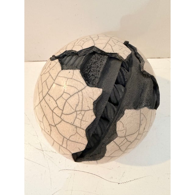Raku-fired ceramic sphere sculpture by artist Michael Mick, featuring a striking crackle glaze surface with a dramatic...