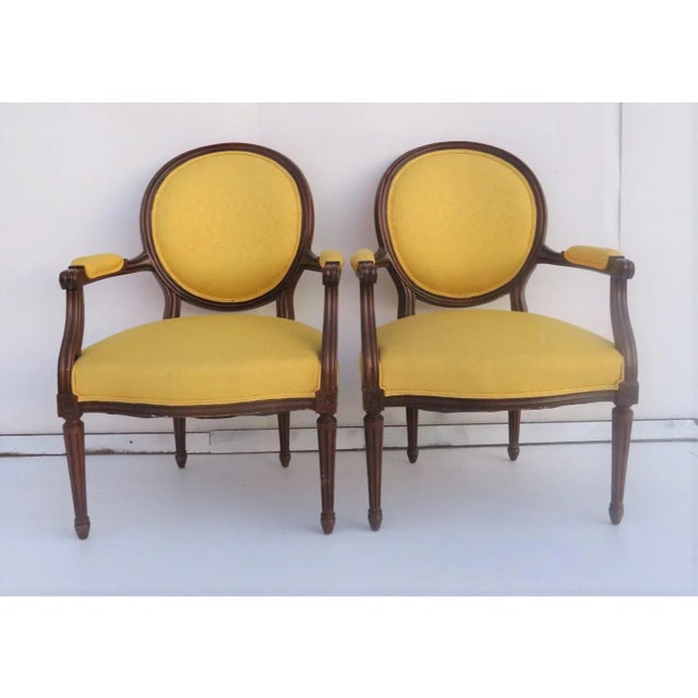 Louis XVI style walnut frames with yellow upholstery and rounded backs.