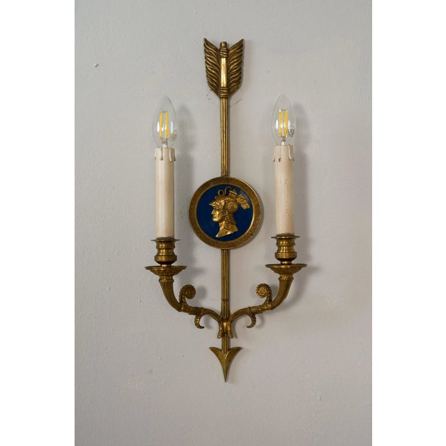 Pair of vintage two-light neoclassical style wall lights. The sconces are adorned with finely detailed medallions...