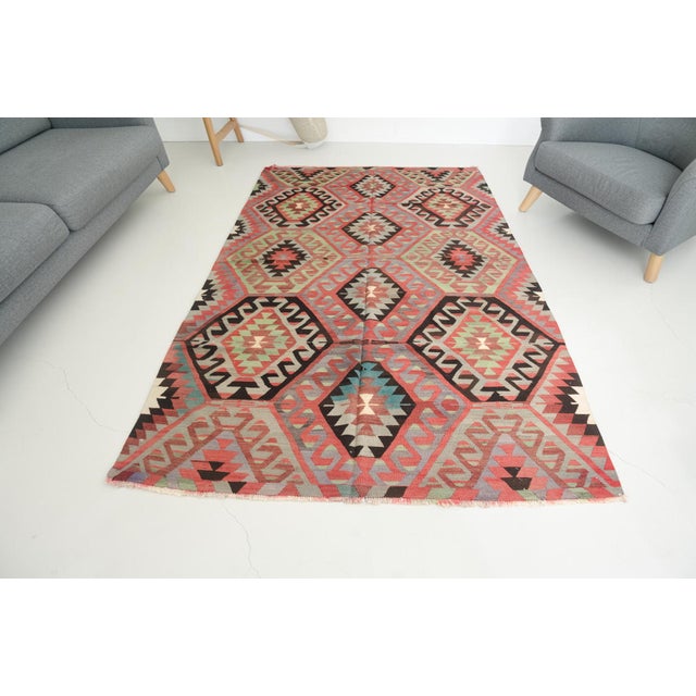 This is a vintage Turkish Oushak rug from the Mid 20th Century. The piece was hand-knotted.