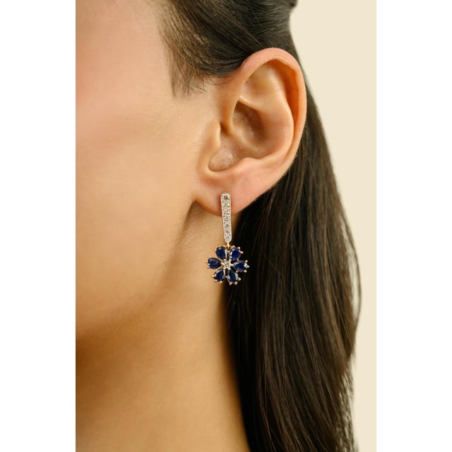 These elegant floral drop earrings features 12 pear-cut blue sapphire totaling 3.77 carats, set in 18k yellow gold. each...