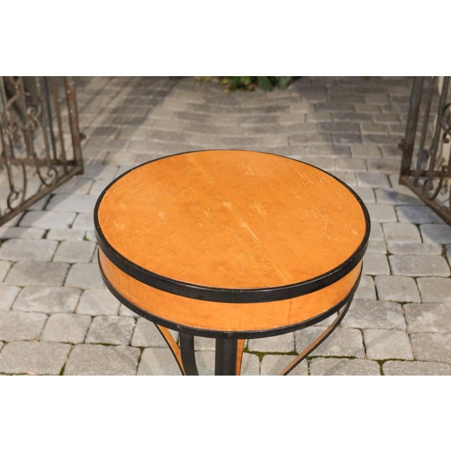 An Austrian Biedermeier period guéridon side table with burl veneer and iron base from the early 19th century. This...