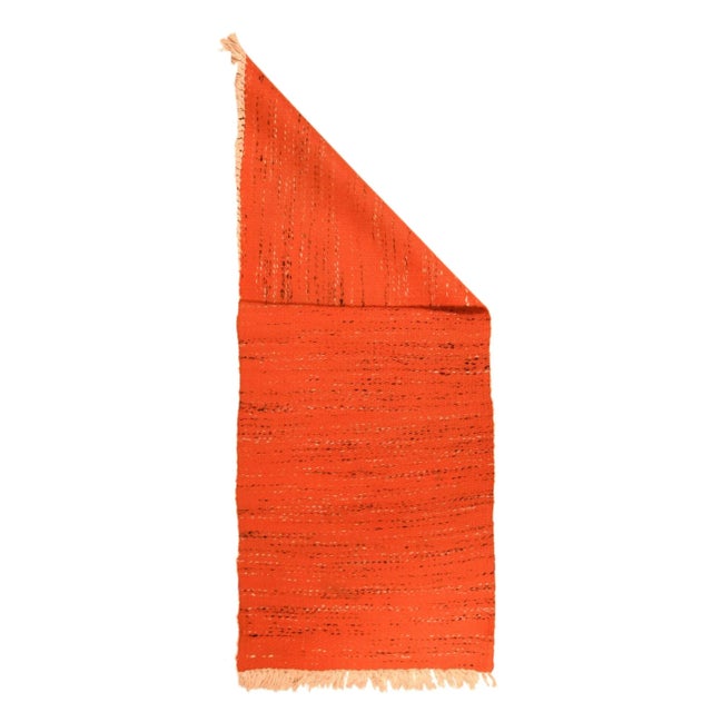 The rust-red wool field of this plain weave kellegi (long rug) is randomly interrupted by broken streaks of yarn in...