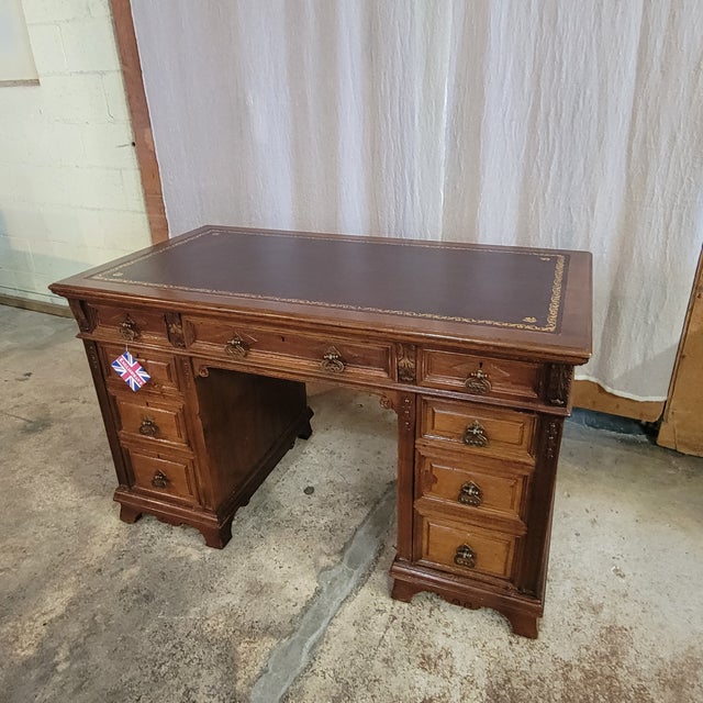 This Antique English Oak Leather Top Pedestal Desk With Acanthus Leaf Carvings is on bracket feet. It has 9 drawers for...