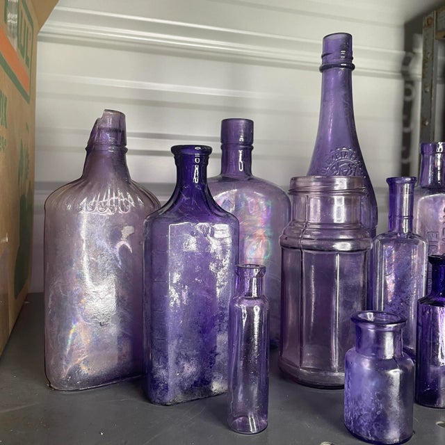 A set of 16 antique purple bottles and jars of varying sizes. Most pieces are free from chips and cracks, but most have a...