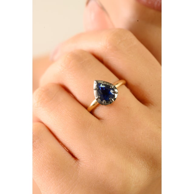 This elegant solitaire ring showcases a striking pear-cut blue sapphire weighing approximately 1.52 carats, set in radiant...