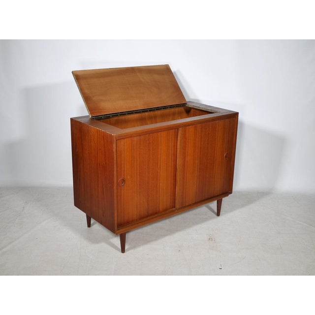 Bar sideboard by Musterring in teak with an integrated drop-down compartment, two sliding doors, and tapered solid wood...