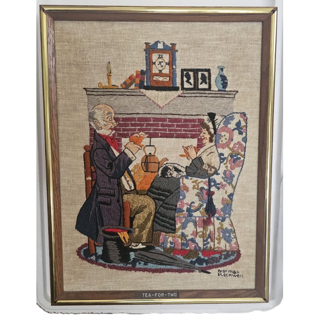A wonderfully nostalgic hand‑stitched needlepoint interpretation of Norman Rockwell’s “Tea for Two,” framed in warm oak...