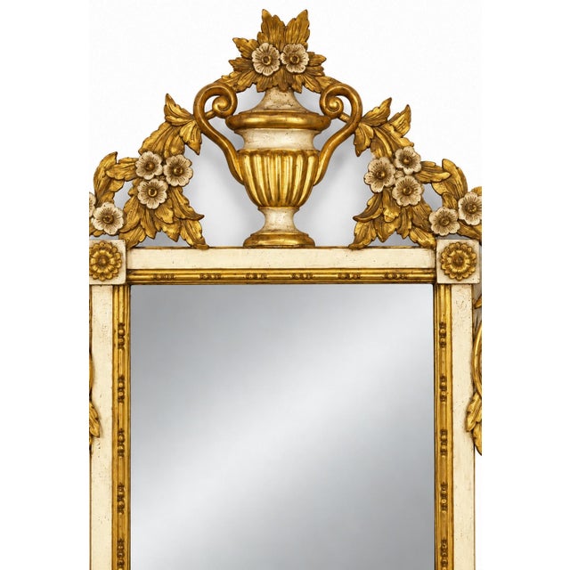 This is a lovely Italian neo-classical style carved giltwood mirror with an urn and floral motif. It dates to the 1960s....