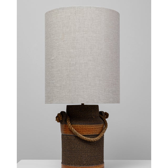 This 20th Century German orange ceramic table lamp with rope handle blends rustic charm with mid-century craftsmanship....