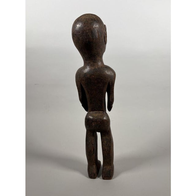 NYAMWEZI, TANZANIA Carved from hardwood with a brown patina and inlaid with bronze rings around the eyes and nipples. This...