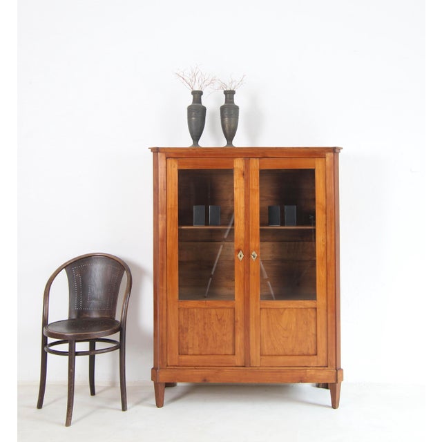 An elegant small Biedermeier display cabinet from the first half of the 19th century. Crafted from solid cherry wood. Good...