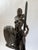 This bronze sculpture presents a powerful African female warrior rendered in a poised yet commanding stance, holding a...