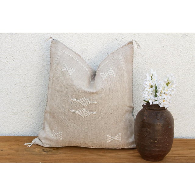 Fine stacked diamond motifs sit beneath soft horizontal dash lines on this handcrafted Moroccan cactus silk pillow, hand-...