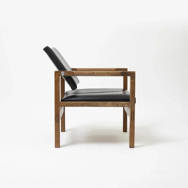 Pair of tiltback armchairs in oak and leatherette, Denmark, 1960s The seat reqires reupholstery, the chairs are...