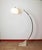 Floor lamp consisting of a base with two travertine slabs, two overlapping curved stems, the upper stem sliding on the...