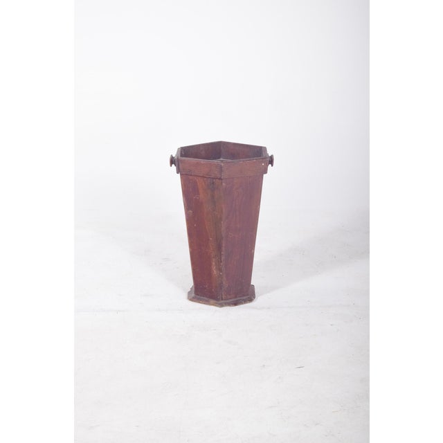 Hexagonal wooden rubbish bin. With a tapered structure towards the base, it has simple side handles for handling. The...