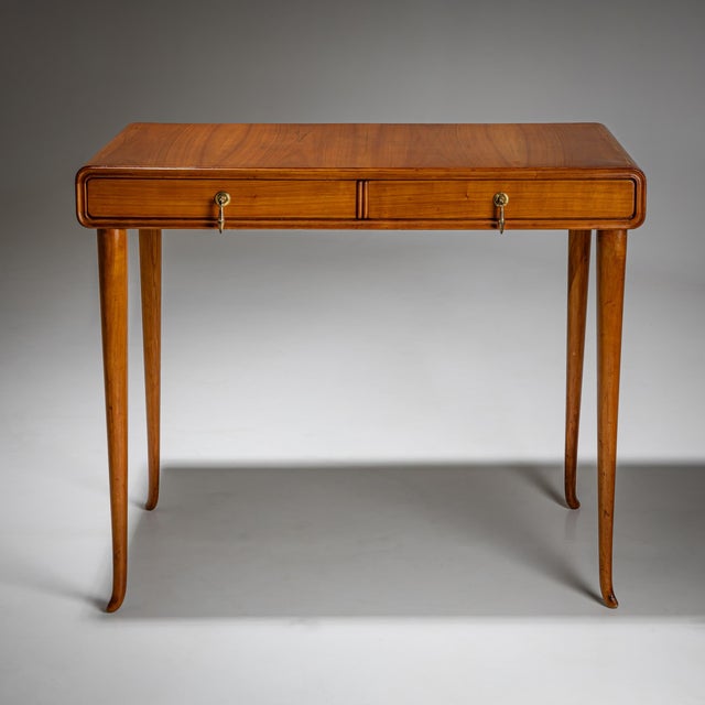 Delicate cherry wood desk with two drawers and tall, slender legs. The drawers are fitted with brass pulls. The rounded...