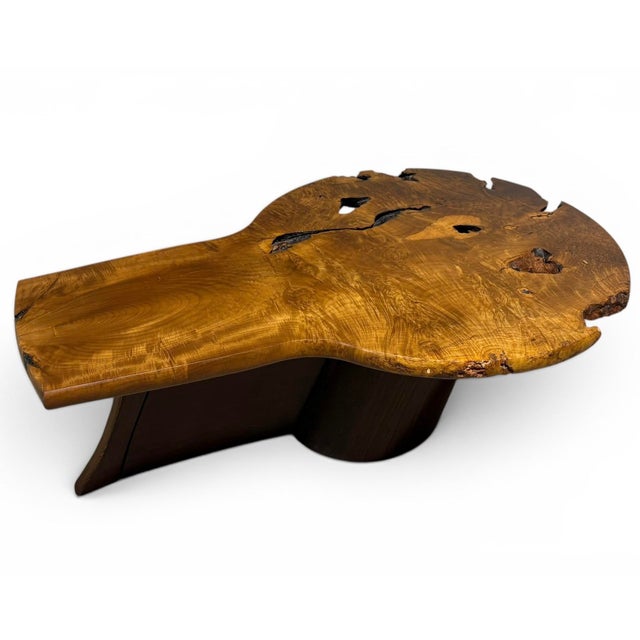 A sculptural burl wood coffee table in the manner of George Nakashima, circa 1980, featuring a key-hole shaped live-edge...
