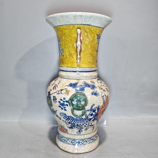 This striking porcelain vase features a vibrant yellow ground adorned with intricate blue and white floral motifs on the...