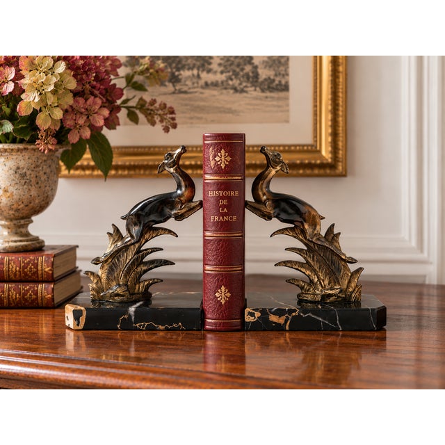 A striking pair of French Art Deco bookends, circa 1930, featuring two graceful leaping antelopes sculpted above stylized...