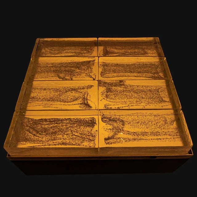 Illuminating coffee table. Black enamelled metal structure with brass edges on base and top. Clear brass bricks top....