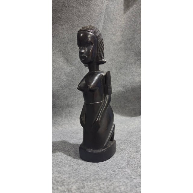 This beautifully hand-carved ebony wood sculpture depicts a graceful kneeling female figure with finely detailed facial...