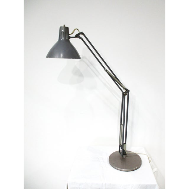 An vintage Luxo L 1 desk or task lamp in industrial gray with adjustable arm, tilting metal shade and heavy stable base....