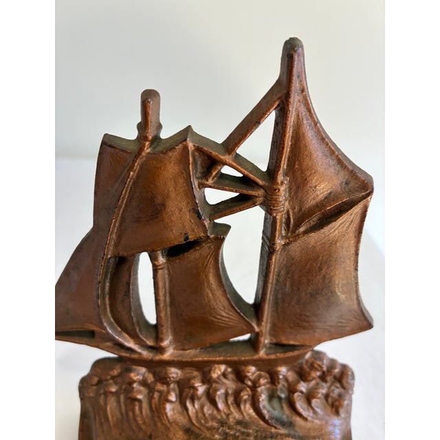 A single vintage cast iron bookend with sculpted sails and waves on a rounded base. Its aged copper-tone finish makes it a...