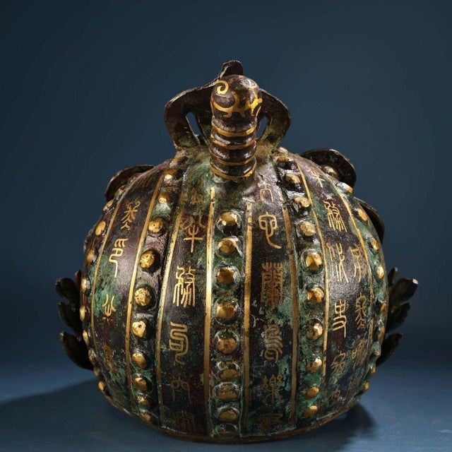 This striking Chinese bronze helmet features an elaborately crafted face mask adorned with traditional gold inlay (cuo...