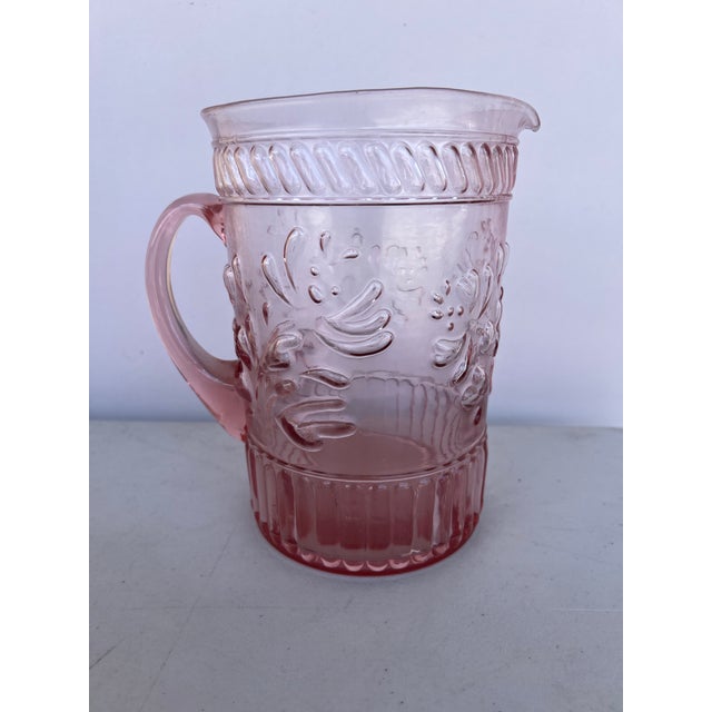Vintage pink thick hand-blown glass water pitcher featuring a decorative molded design. Transparent pink Glass with...