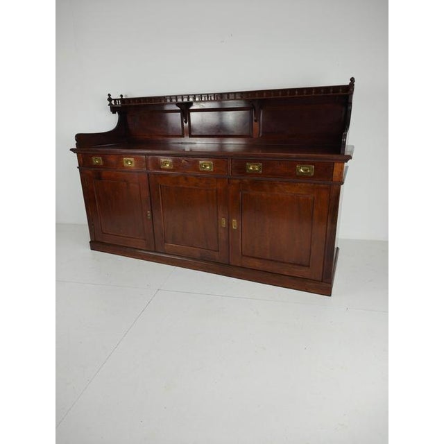 Elegant and generously proportioned dresser or sideboard, crafted in England from solid mahogany with classic brass...