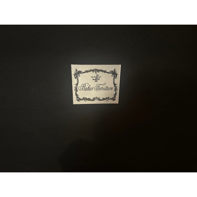 Black leather ottoman serves as a coffee table. The top has stitched detailing in an X pattern. The dark wood base...