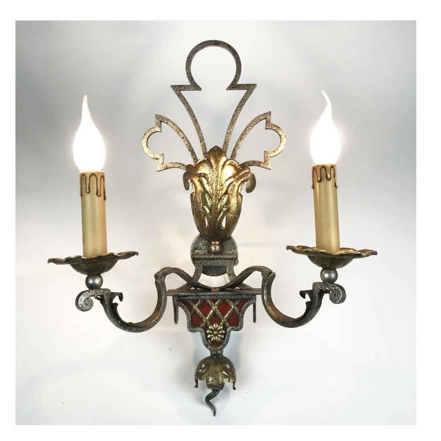 A pair of silver- and gold-plated iron wall sconces, ideal for illuminating any classic decor, are crafted from forged and...