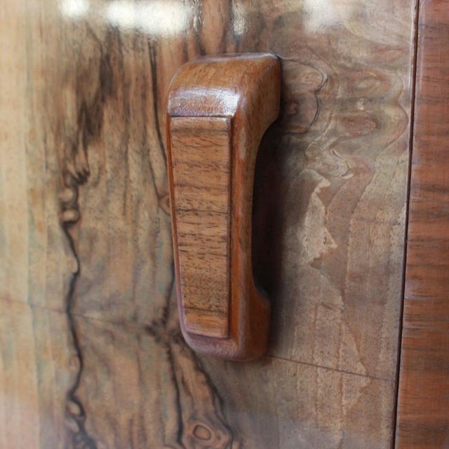 A pair of art deco bedside cabinets in figured walnut with original wooden handles. Drawer to top with shelved cabinet...