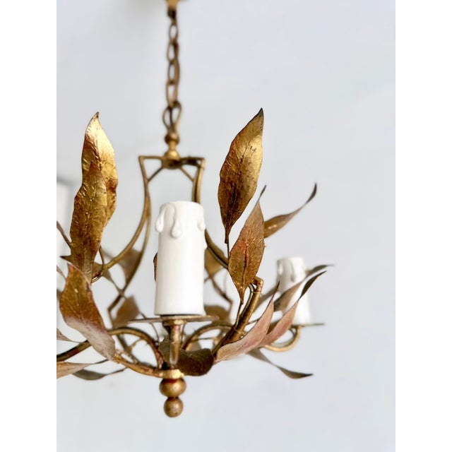 Vintage gilt tole chandelier with four candle-style light arms and hand-formed leaf decoration. Constructed of gilt-...