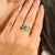 Bold and contemporary, this eye-catching ring features two radiant emerald-cut green emeralds totaling 1.37 carats. The...