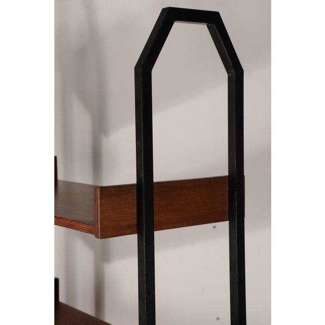 Vintage bookcase from Italy in the 1960s. Composed of two black lacquered metal uprights on adjustable glides, each with a...