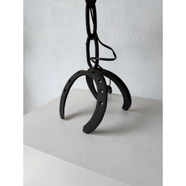 Table lamp with its “chain” pattern base resting on a pair of horseshoes, brutalist style. Entirely handcrafted and...