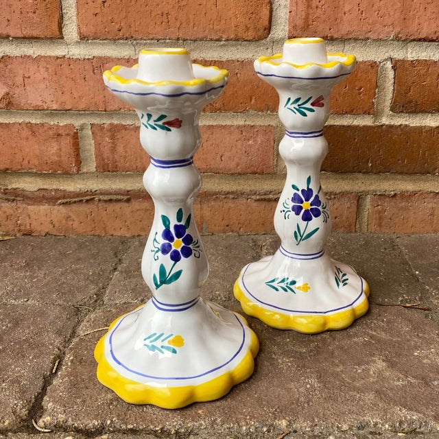 Lovely pair of hand painted white pottery candlesticks featuring delicate flowers and canary yellow scalloped edges....