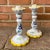 Lovely pair of hand painted white pottery candlesticks featuring delicate flowers and canary yellow scalloped edges....