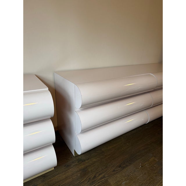 A striking 1980s postmodern bedroom set featuring a low-profile dresser and matching nightstand in a soft mauve lacquer...