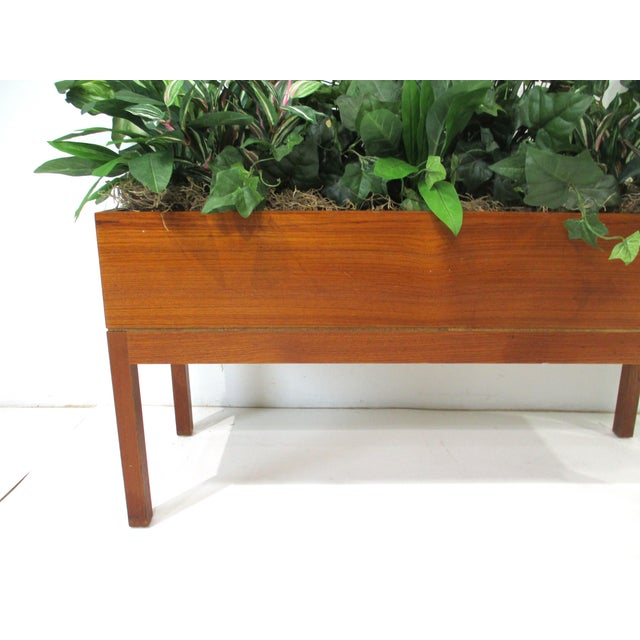 A very nice sized Mid Century teak wood indoor planter professionally potted with silk faux plants and grasses in a bed of...