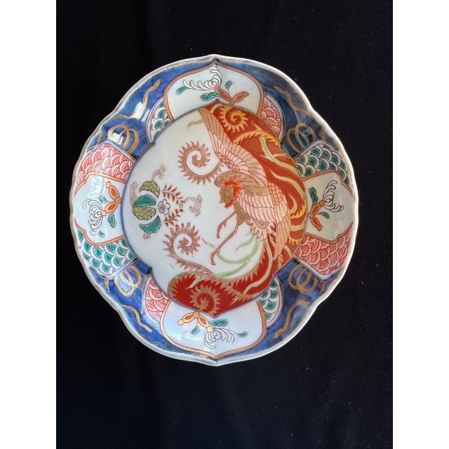 A finely painted Japanese Imari porcelain dish dating to the late Edo to early Meiji period, featuring a dynamic phoenix...
