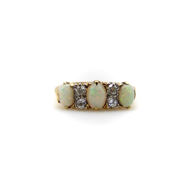This 18k gold Edwardian ring features three oval Australian opals prong set with four small diamonds encrusted between...