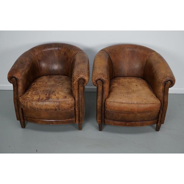 This pair of cognac-colored leather club chairs come from the Netherlands. They are upholstered with cognac-colored...