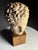 Sculpture of a Greek head. Made of plaster. On a wooden base. Dimensions: 46H x 21W x 25D cm
