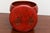A small antique Chinese red lacquered covered box with a rounded, bulbous form, two painted figures at play amid floral...